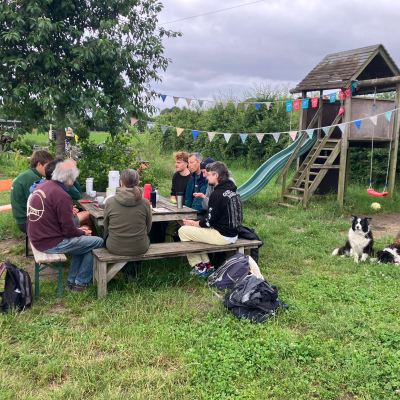 Foto van 8 Landgenoten-vrijwilligers aan picknicktafel die vergaderen